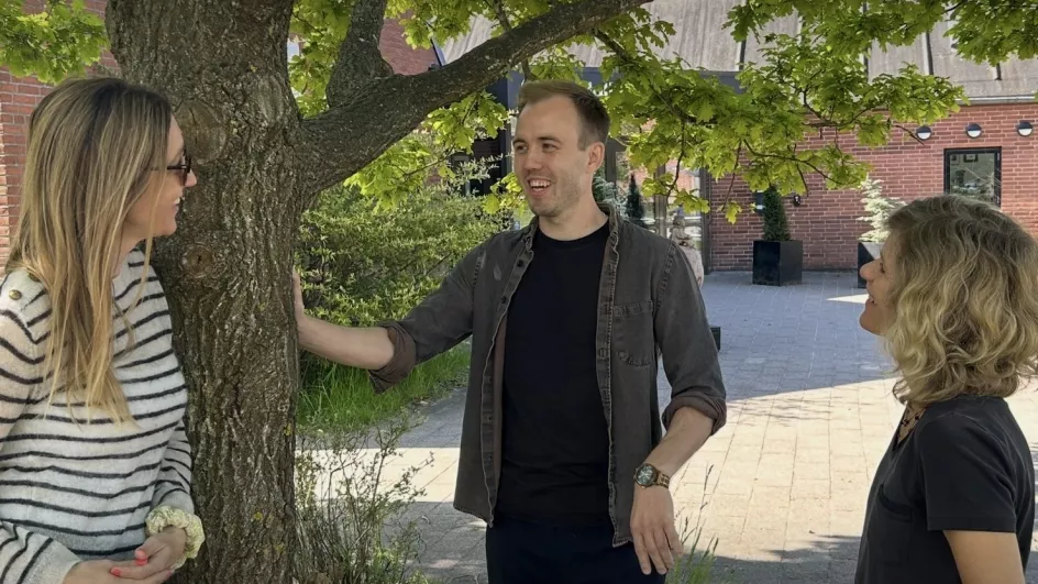 Karrierelærer står under et træ i skolegården og taler med skoleleder og UU-vejleder